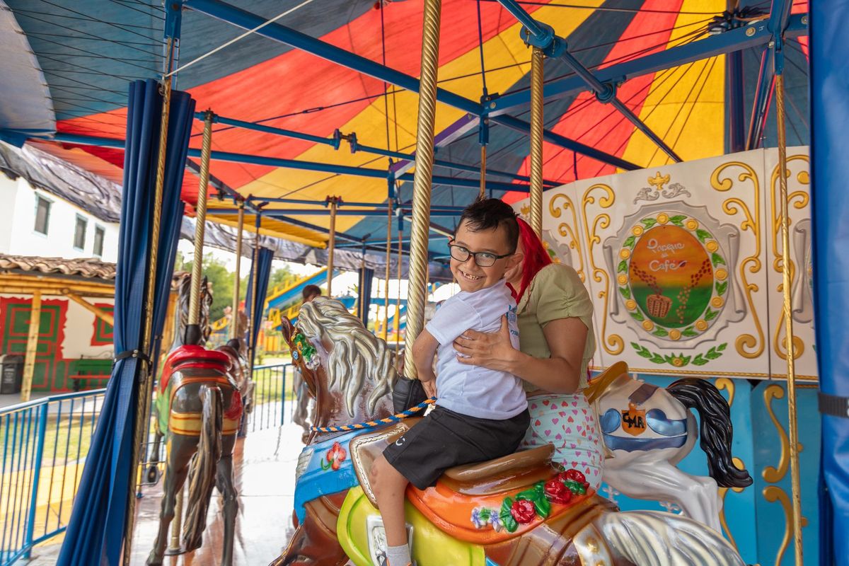 Un niño en el carrusel junto a su mamá